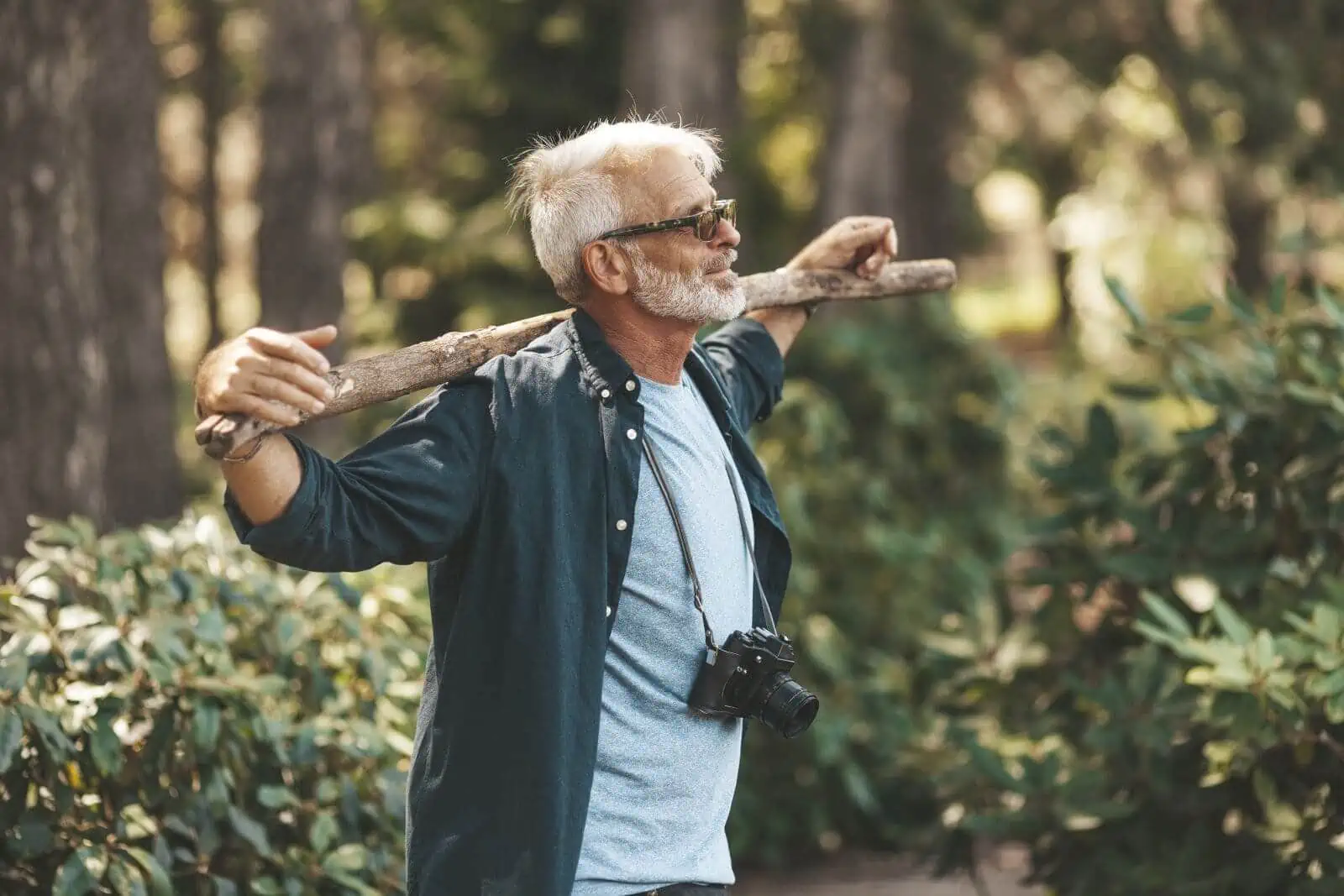Mature man holding walking stick and camera