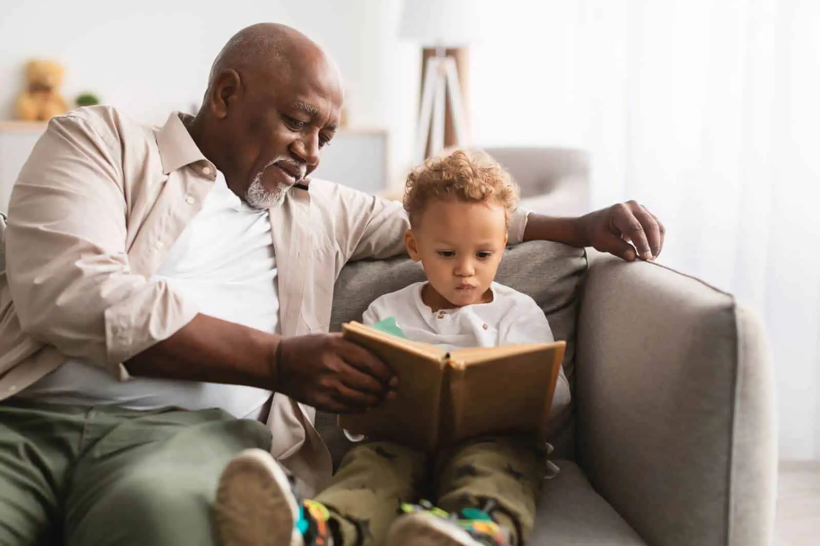 Grandfather helping grandson to read a book