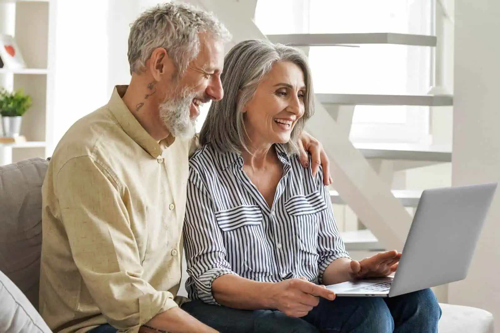 Middle aged couple looking at hearing aids on laptop